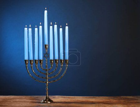 Téléchargez les photos : Hanoukka fête. Menorah avec des bougies allumées sur table en bois sur fond bleu, espace pour le texte - en image libre de droit