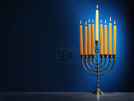 Téléchargez les photos : Hanoukka fête. Menorah avec des bougies allumées sur la table sur fond bleu, espace pour le texte - en image libre de droit