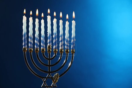 Téléchargez les photos : Hanoukka fête. Menorah avec des bougies brûlantes sur fond bleu, espace pour le texte - en image libre de droit