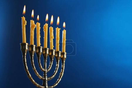 Téléchargez les photos : Hanoukka fête. Menorah avec des bougies brûlantes sur fond bleu, gros plan et espace pour le texte - en image libre de droit