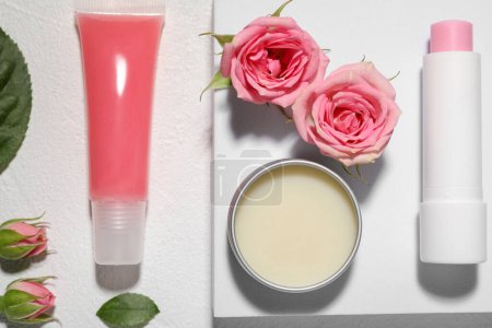 Photo for Flat lay composition with lip balms and rose flowers on white textured background - Royalty Free Image