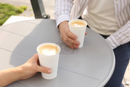 Foto de Café para llevar. Pareja con vasos de papel en la mesa gris al aire libre, primer plano - Imagen libre de derechos