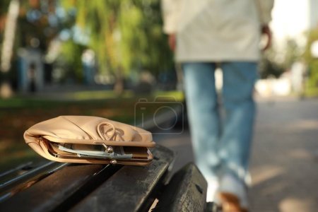 Mujer perdió su bolso en la superficie de madera al aire libre, enfoque selectivo