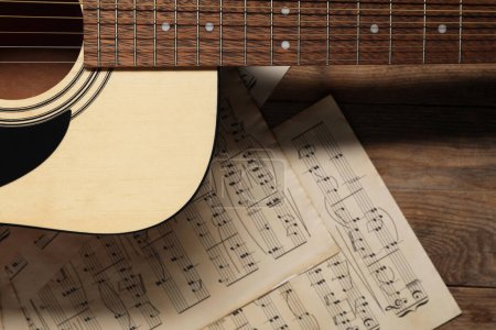 Téléchargez les photos : Feuilles de papier avec notes de musique et guitare acoustique sur table en bois, vue de dessus - en image libre de droit