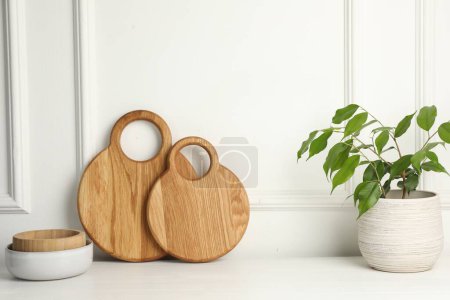Foto de Tableros de madera para cortar, cuencos y plantas de interior sobre mesa blanca - Imagen libre de derechos