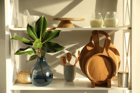 Foto de Madera tablas de cortar, utensilios, rama con hojas verdes y decoración en la unidad de estanterías - Imagen libre de derechos