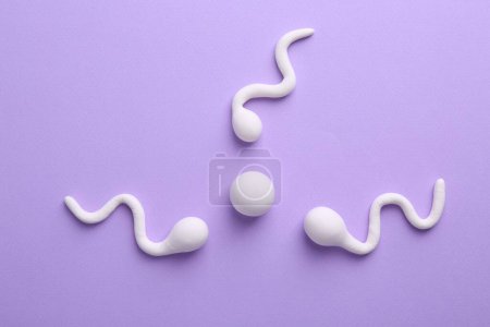 Foto de Concepto de fertilización. Células de esperma nadando hacia el óvulo sobre fondo violeta, vista superior - Imagen libre de derechos