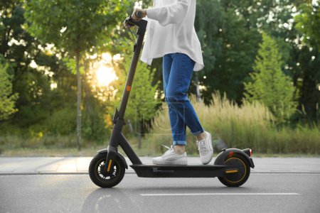 Photo for Woman riding modern electric kick scooter in park, closeup - Royalty Free Image