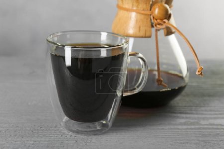Photo for Glass and chemex coffeemaker with tasty drip coffee on grey wooden table, closeup - Royalty Free Image