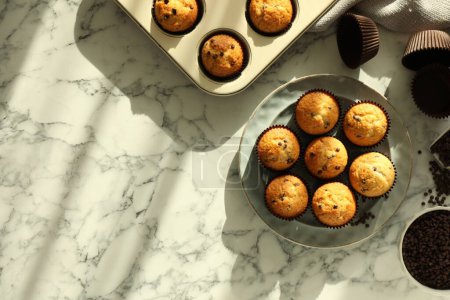 Photo for Delicious sweet muffins with chocolate chips on white marble table, flat lay. Space for text - Royalty Free Image