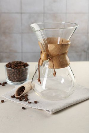 Photo for Empty glass chemex coffeemaker with and beans on white table - Royalty Free Image