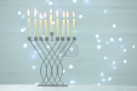 Téléchargez les photos : Hanoukka fête. Menorah avec des bougies allumées sur la table contre les lumières floues, espace pour le texte - en image libre de droit