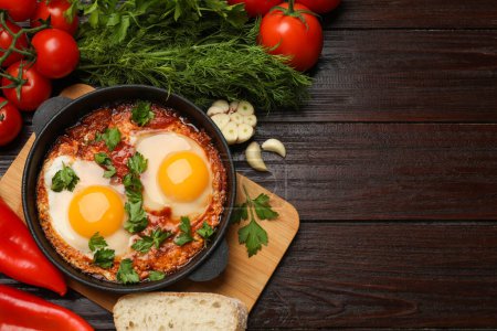 Flat lay composition with delicious shakshuka in frying pan on wooden table. Space for text