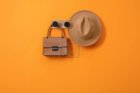 Photo for Rack with brown hat and bag on orange wall, space for text - Royalty Free Image