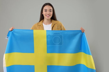 Mujer joven con bandera de Suecia sobre fondo gris claro