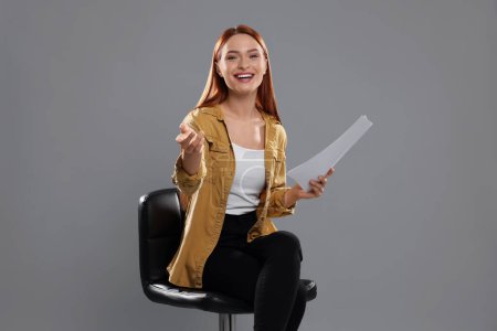 Casting call. Young woman with script performing on grey background
