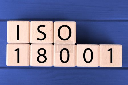 Organisation internationale de normalisation. Cubes avec abréviation ISO et numéro 18001 sur table en bois bleu, pose plate
