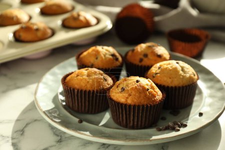 Photo for Delicious sweet muffins with chocolate chips on white marble table - Royalty Free Image