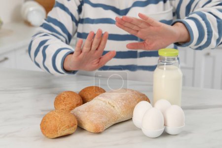 Foto de Mujer que sufre de alergias alimentarias se niega a comer diferentes productos frescos en la mesa de mármol ligero en el interior, primer plano - Imagen libre de derechos