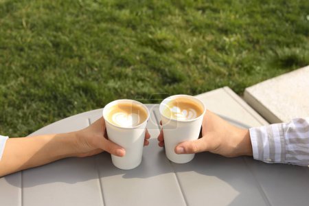 Foto de Café para llevar. Pareja con vasos de papel en la mesa gris al aire libre, primer plano - Imagen libre de derechos
