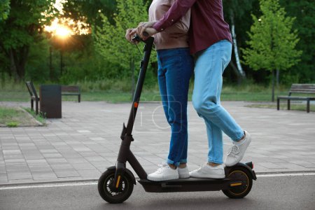 Photo for Couple riding modern electric kick scooter in park, closeup - Royalty Free Image