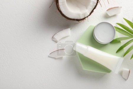 Lip balms, coconut and leaves on white background, flat lay. Space for text