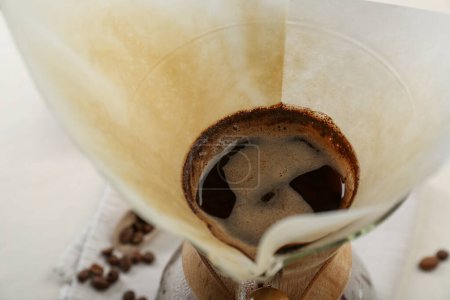 Foto de Elaboración de café de goteo aromático en cafetera chemex con filtro de papel en la mesa, primer plano - Imagen libre de derechos