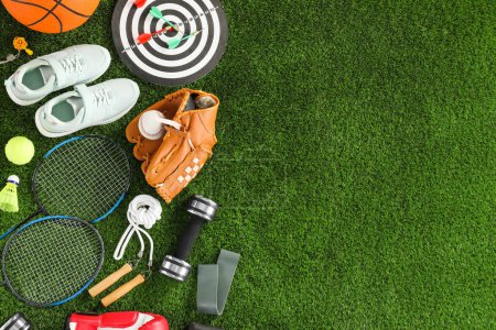 Téléchargez les photos : Différents équipements sportifs et baskets sur herbe verte, plat. Espace pour le texte - en image libre de droit