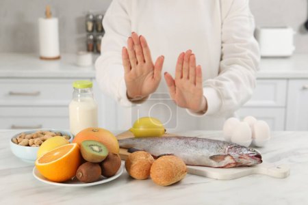 Foto de Mujer que sufre de alergias alimentarias se niega a comer diferentes productos frescos en la mesa de luz en el interior, primer plano - Imagen libre de derechos