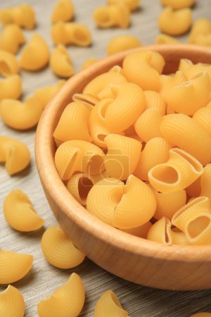 Raw macaroni pasta on wooden table, closeup