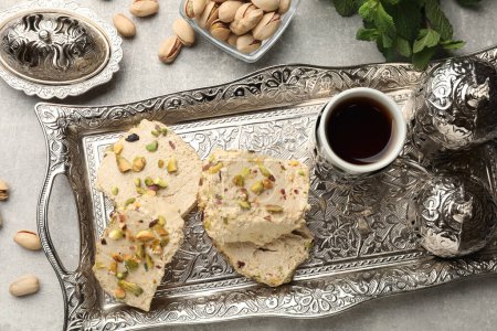 Tasty halva with pistachios served on grey table, flat lay