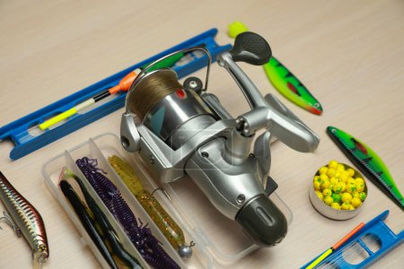 Different fishing equipment on light wooden table, closeup