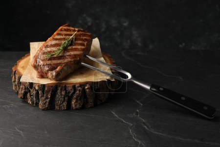 Delicious grilled beef steak served with rosemary on dark gray table