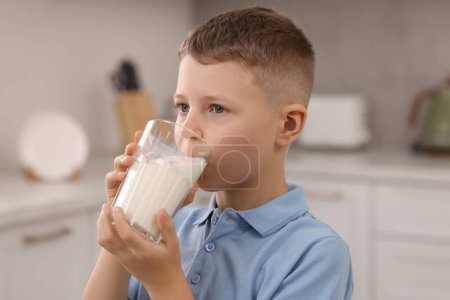 Téléchargez les photos : Mignon garçon boire du lait frais à partir de verre à l'intérieur - en image libre de droit