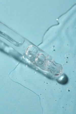 Téléchargez les photos : Sérum cosmétique dégoulinant de la pipette sur fond bleu clair, vue macro - en image libre de droit