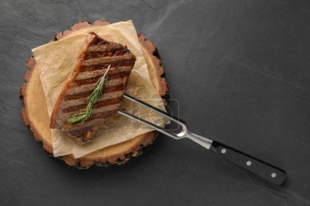 Delicious grilled beef steak and rosemary on dark gray table, top view