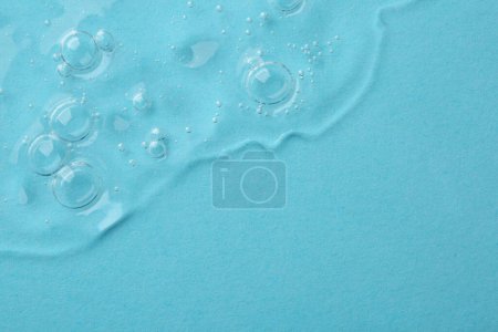 Photo for Clear cosmetic serum on light blue background, top view. Space for text - Royalty Free Image