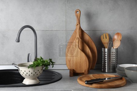 Foto de Tableros de cortar de madera, otros utensilios de cocina y vajilla en encimera gris claro en la cocina - Imagen libre de derechos