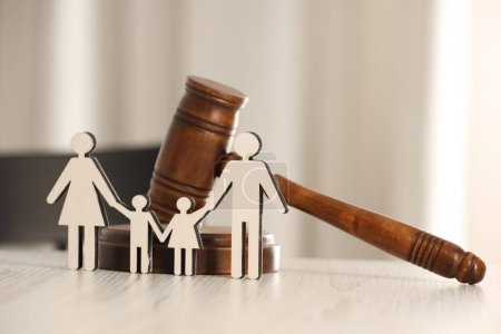 Law concept. Gavel and figures of parents with children on white wooden table, closeup