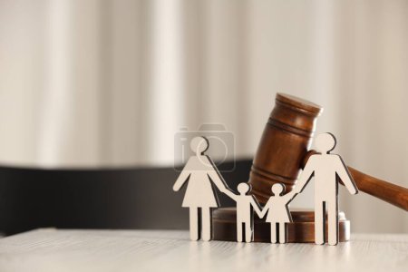 Law concept. Gavel and figures of parents with children on white wooden table, space for text