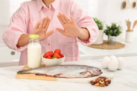 Foto de Mujer que sufre de alergias alimentarias se niega a comer diferentes productos frescos en la mesa de luz en el interior, primer plano - Imagen libre de derechos