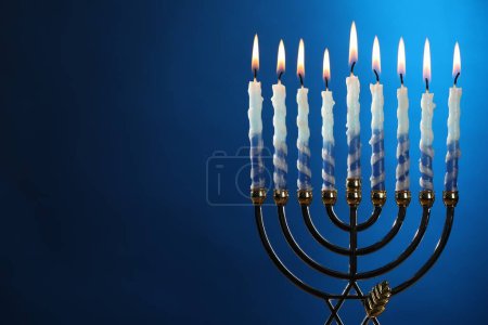 Téléchargez les photos : Hanoukka fête. Menorah avec des bougies brûlantes sur fond bleu, espace pour le texte - en image libre de droit