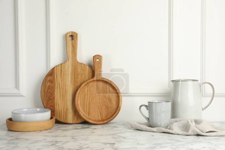Foto de Tableros de madera para cortar, vajilla y toalla sobre mesa de mármol blanco - Imagen libre de derechos