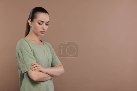Photo for Portrait of resentful woman with crossed arms on brown background. Space for text - Royalty Free Image