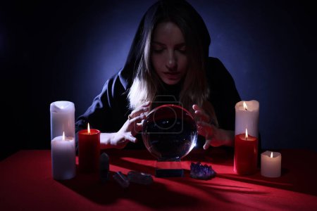 Photo for Soothsayer using crystal ball to predict future at table in darkness. Fortune telling - Royalty Free Image