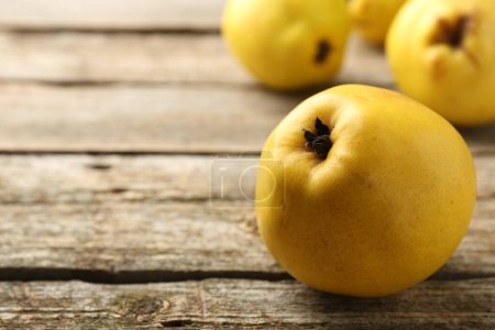 Tasty ripe quinces on wooden table, closeup. Space for text