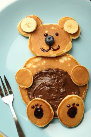 Foto de Servicio creativo para niños. Placa con oso lindo hecha de panqueques, arándanos, plátanos y pasta de chocolate, vista superior - Imagen libre de derechos
