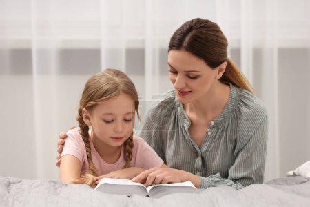 Photo for Girl and her godparent reading Bible together at home - Royalty Free Image