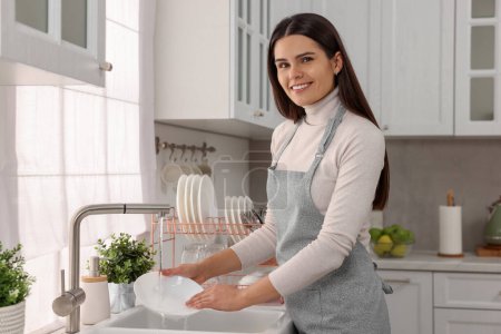 Foto de Mujer feliz lavabo en el fregadero en la cocina - Imagen libre de derechos