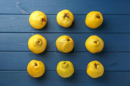 Tasty ripe quinces on blue wooden table, flat lay